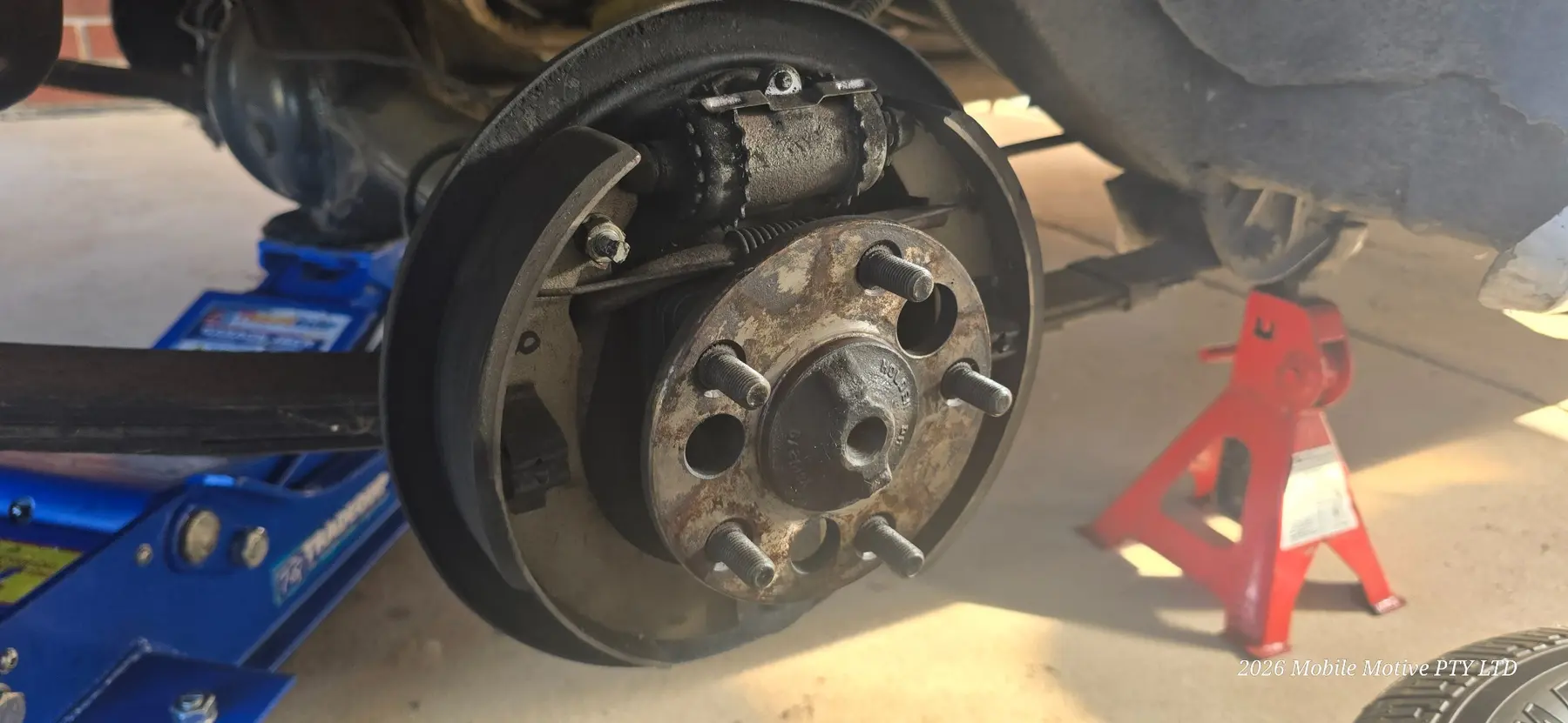 Rear drum brake shoes, wheel cylinder and hub exposed for inspection by Mobile Motive